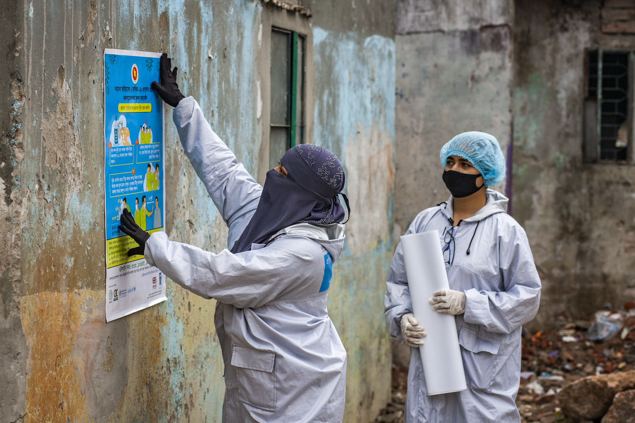 Community health workers sticking posters about COVID-19 prevention