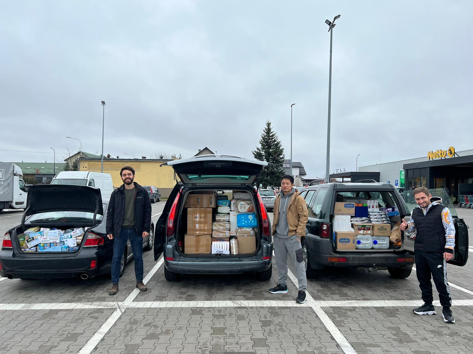 Victor Lal pictured with two colleagues in Poland with cars full of supplies for Ukrainian refugees
