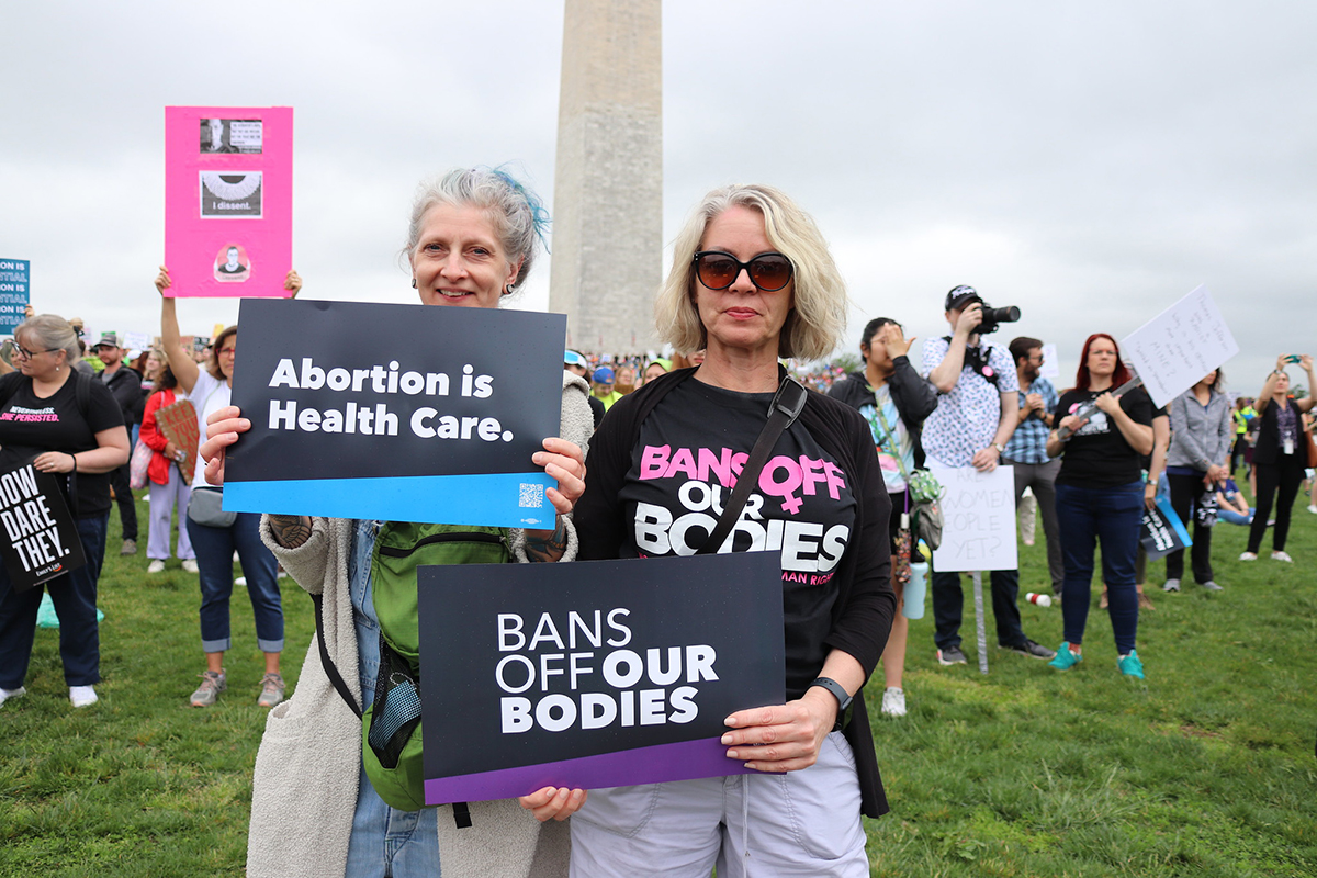 Two women holding placards with 'Bans off our bodies' messages at a rally