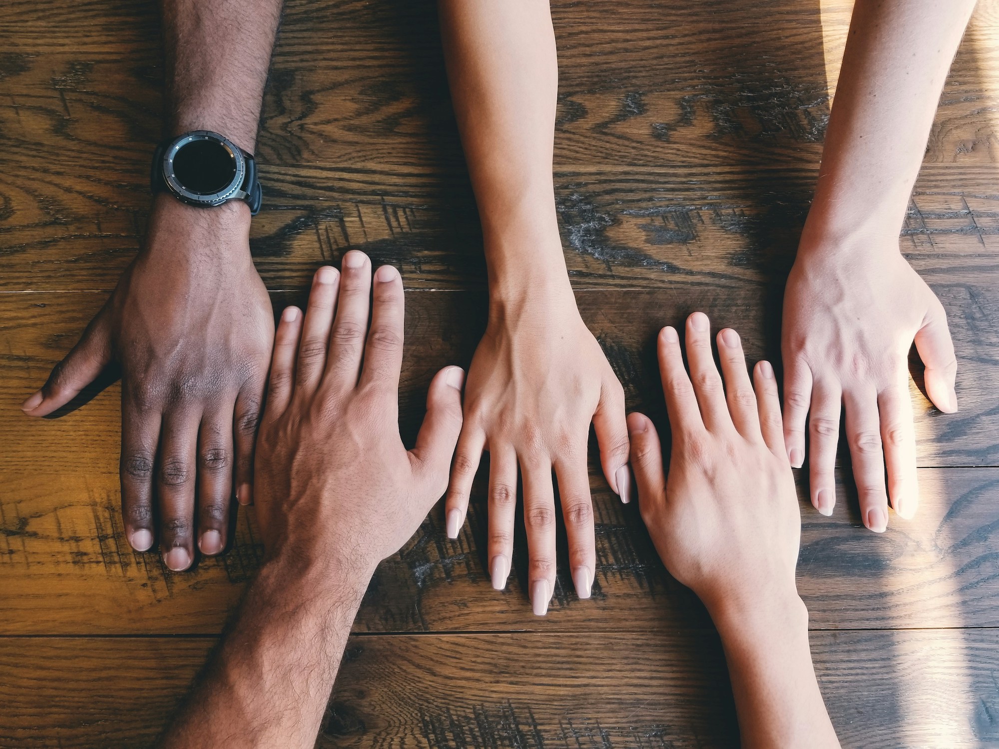 picture of four hands on a table