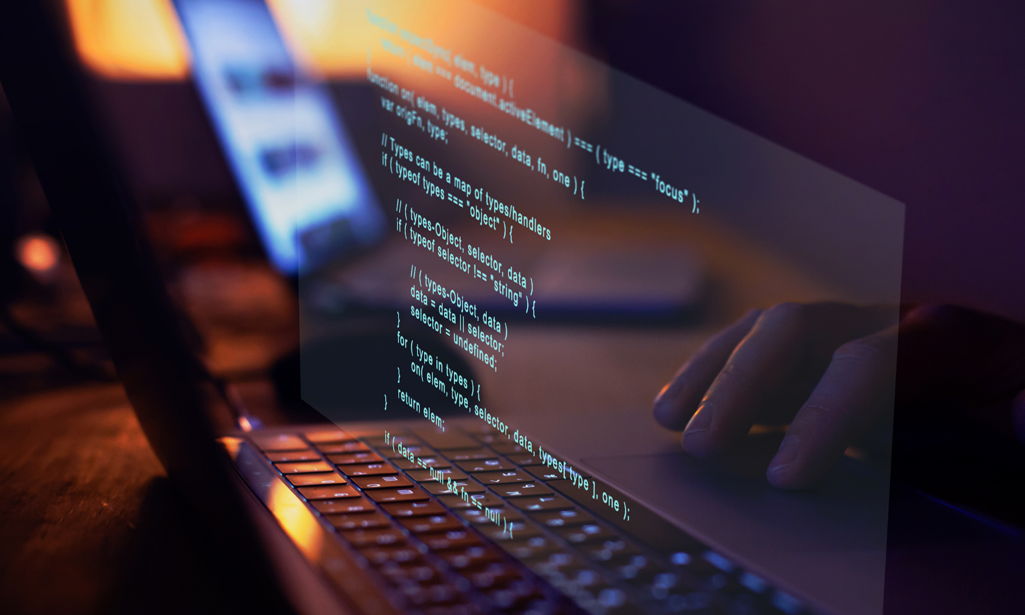 A close-up of a person typing on a laptop keyboard with lines of code projected or digitally superimposed above the keyboard. The background is softly blurred, showing another screen and a dimly lit workspace, creating a focused and tech-centric atmosphere.