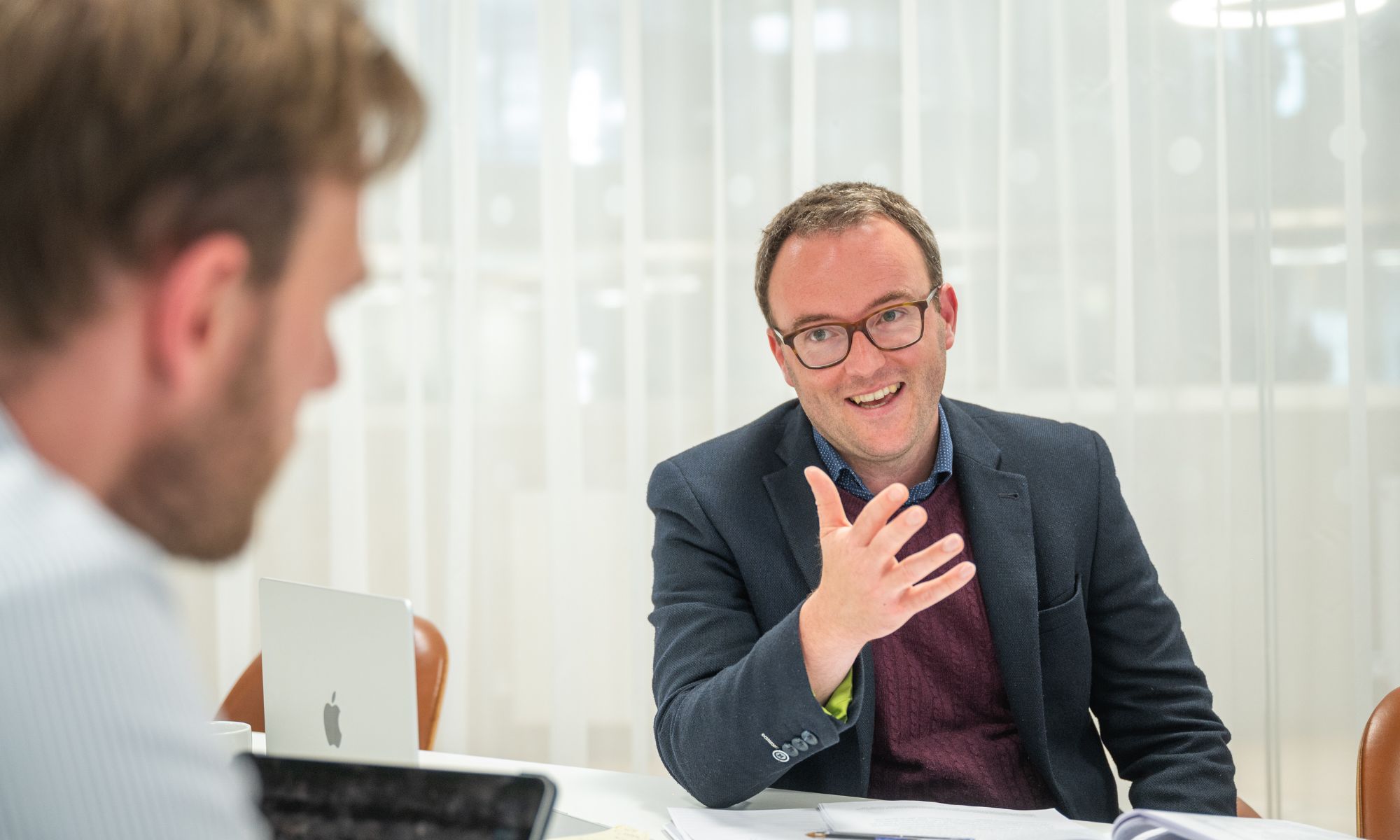 Tom Elston is the focus of the image. He is in conversation with a man who is in the forefront of the image blurred.