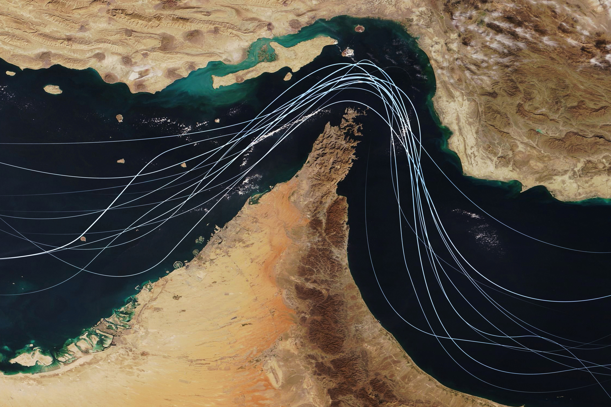 Satellite view of the Strait of Hormuz with white graphic lines representing global shipping lanes and maritime traffic between the Persian Gulf and Gulf of Oman. 