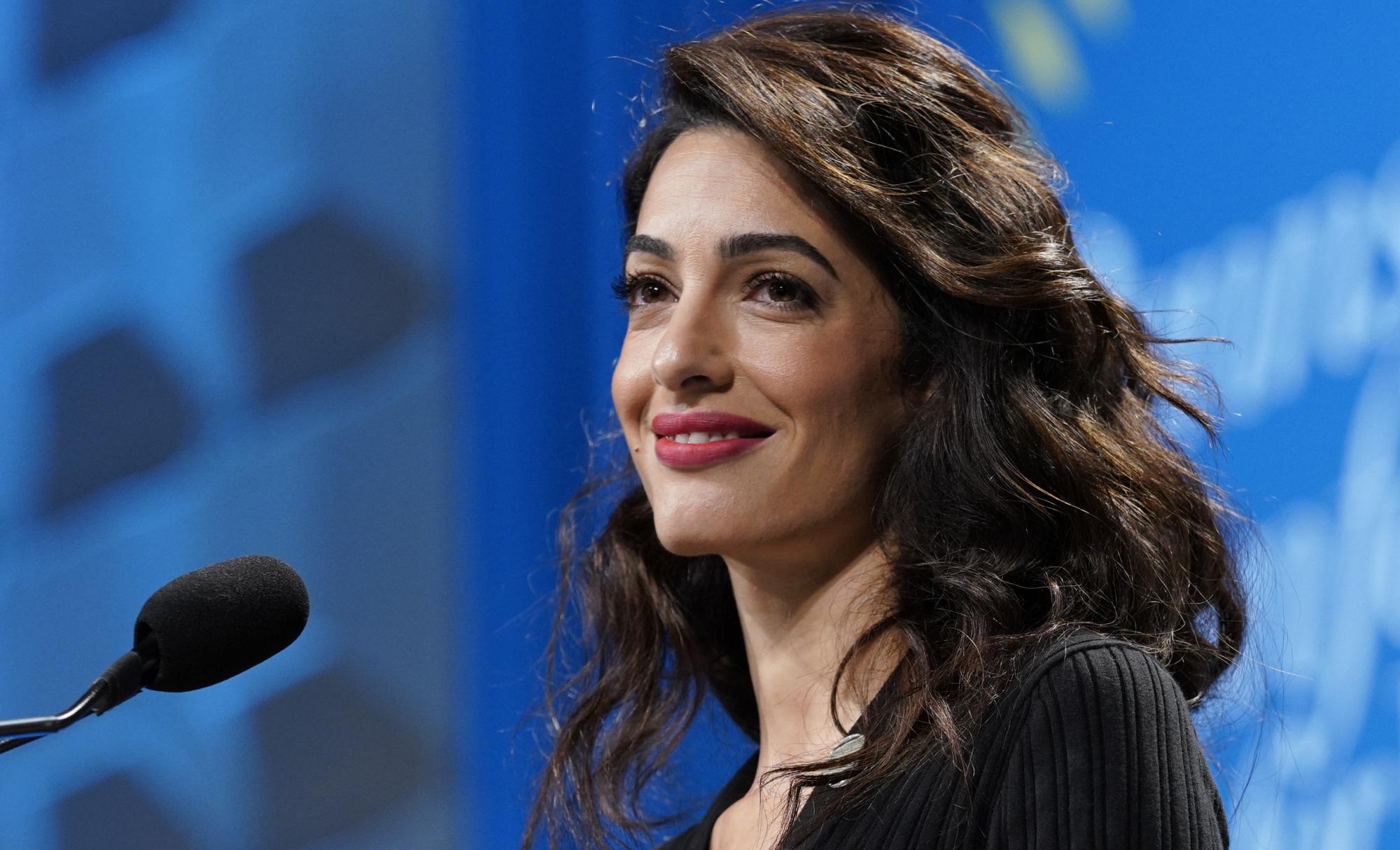 Amal Clooney stands at a conference podium