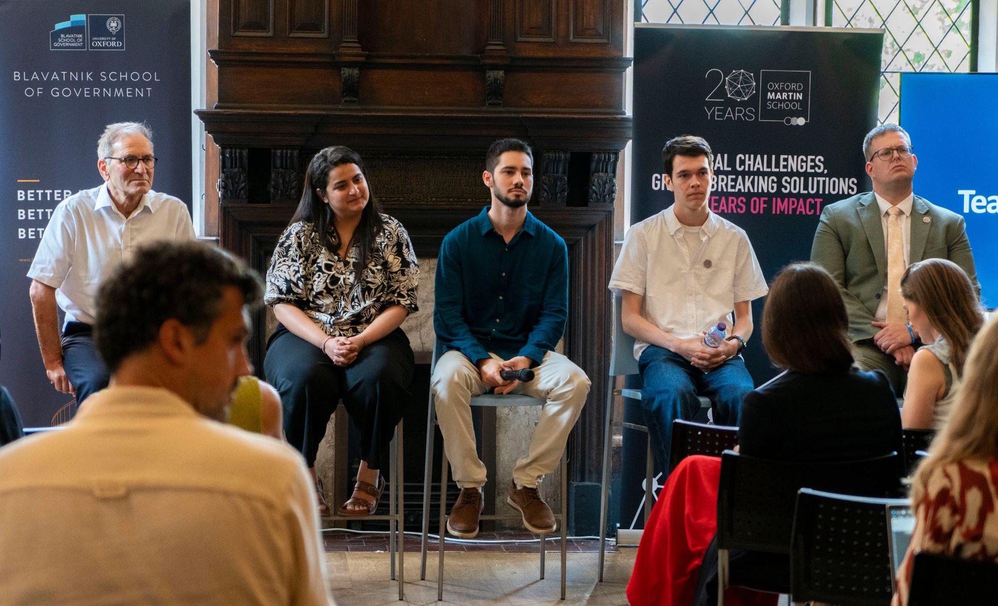 Panel at London Climate week, sat in front of crowd with branded banners behind