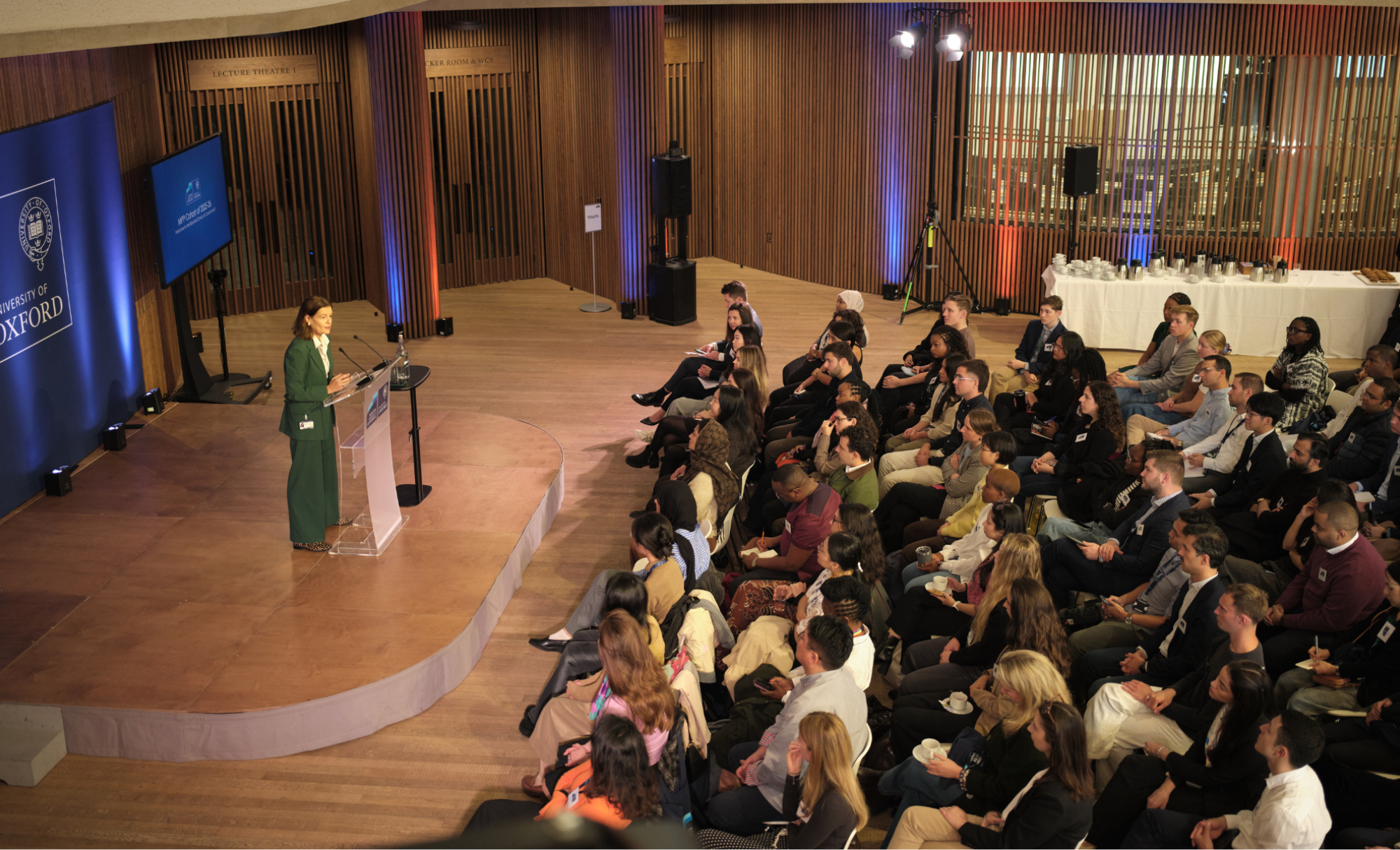 Ngaire Woods gives speech at a lecturn on a small stage as seated students listen