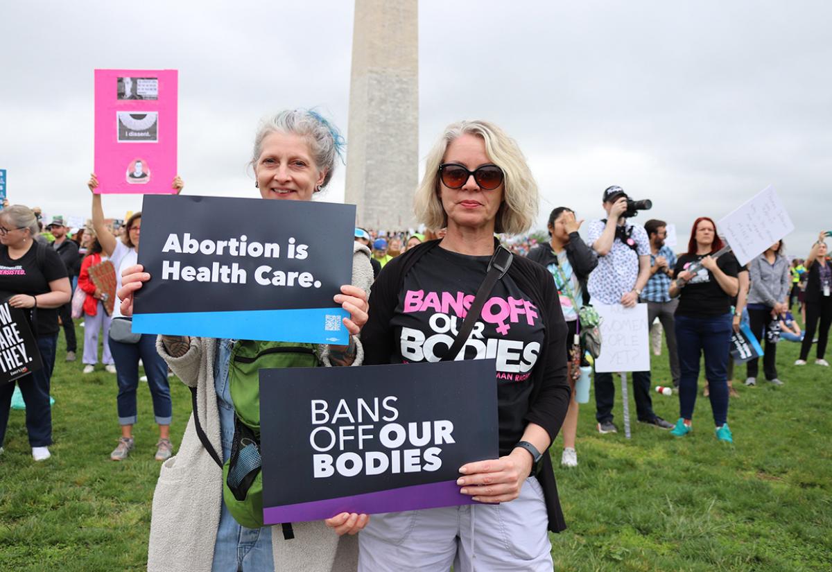 Two women holding placards with 'Bans off our bodies' messages at a rally