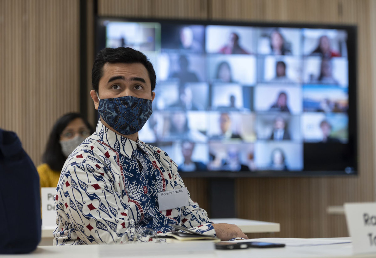 MPP student sitting at a desk during the induction period, with students onscreen in the background as part of hybrid induction