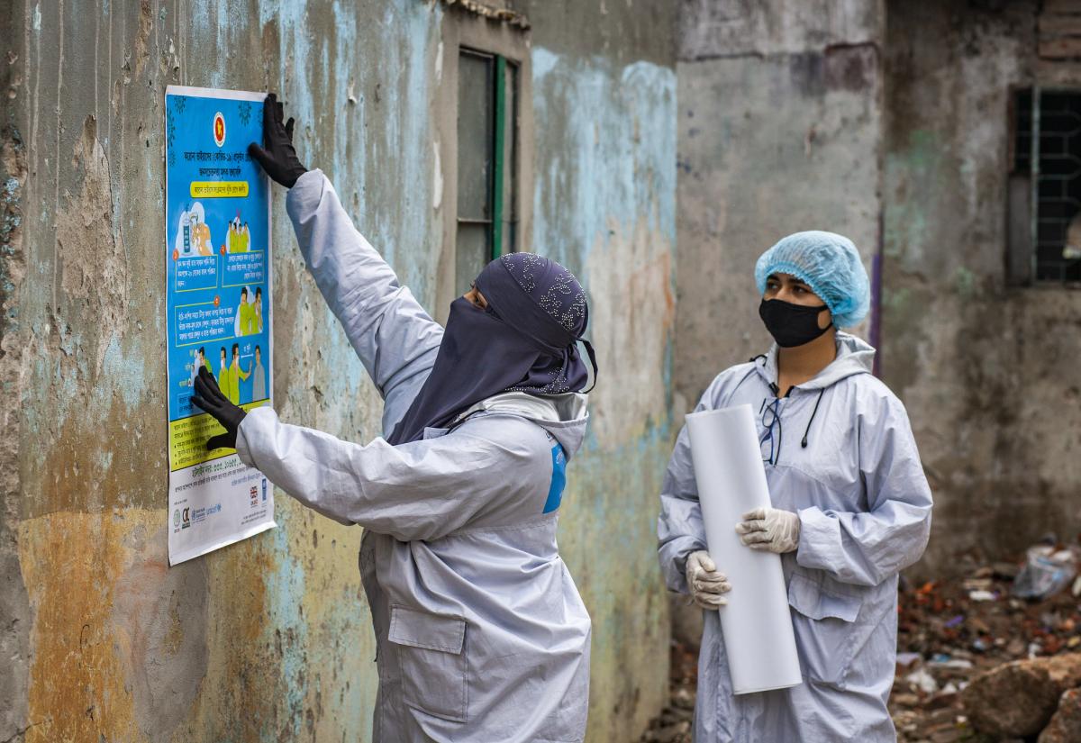 Community health workers sticking posters about COVID-19 prevention