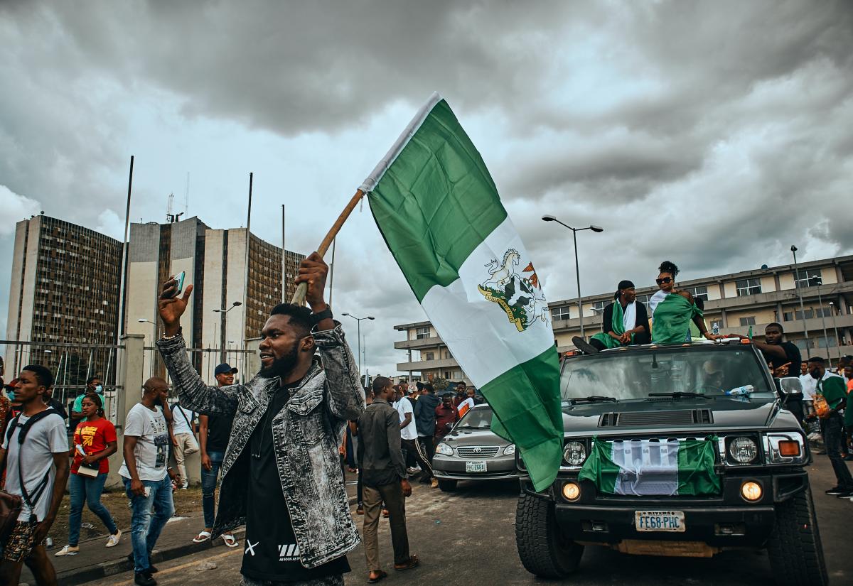 Protestors on foot and in cars holding the Nigerian flag