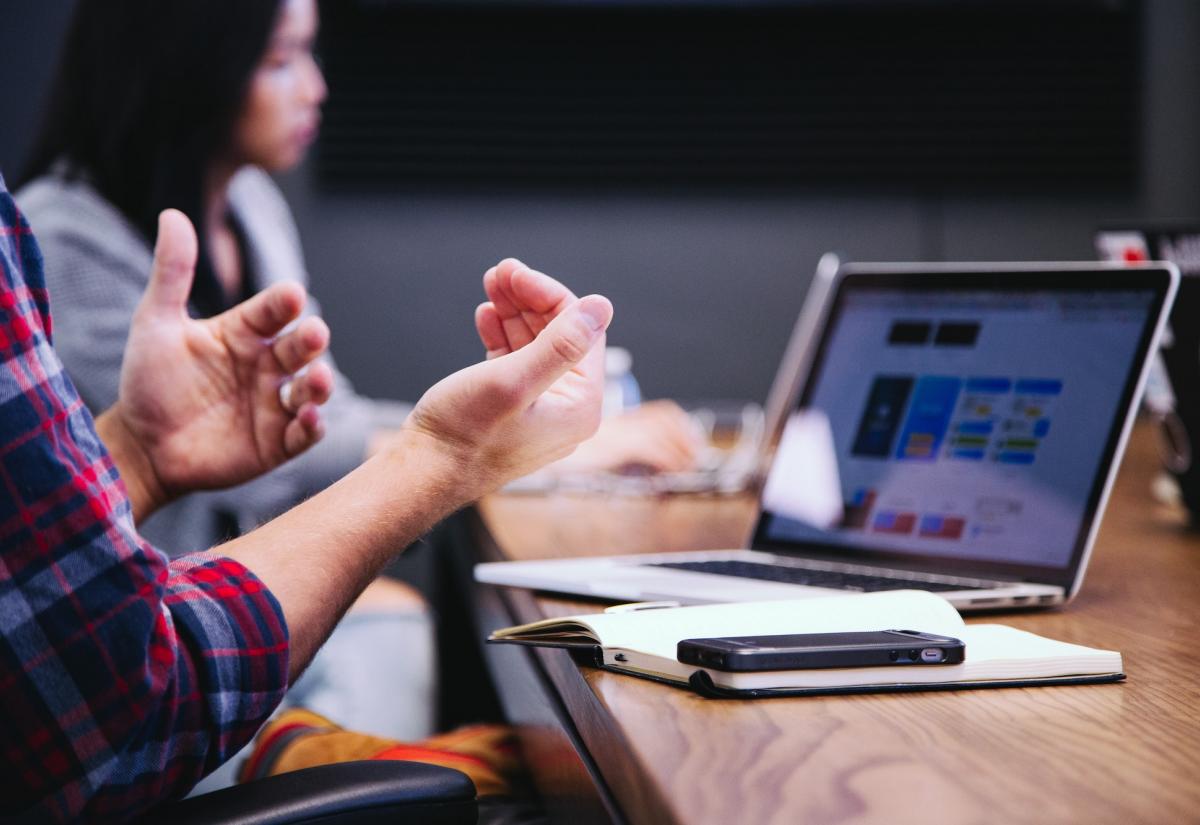 Business meeting with a man on his laptop gesturing with hands