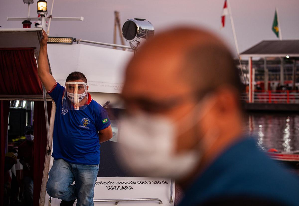 A passenger wearing protective equipment awaits the departure of a speedboat in Manaus, Brazil in 2020. IMF / Raphael Alves 