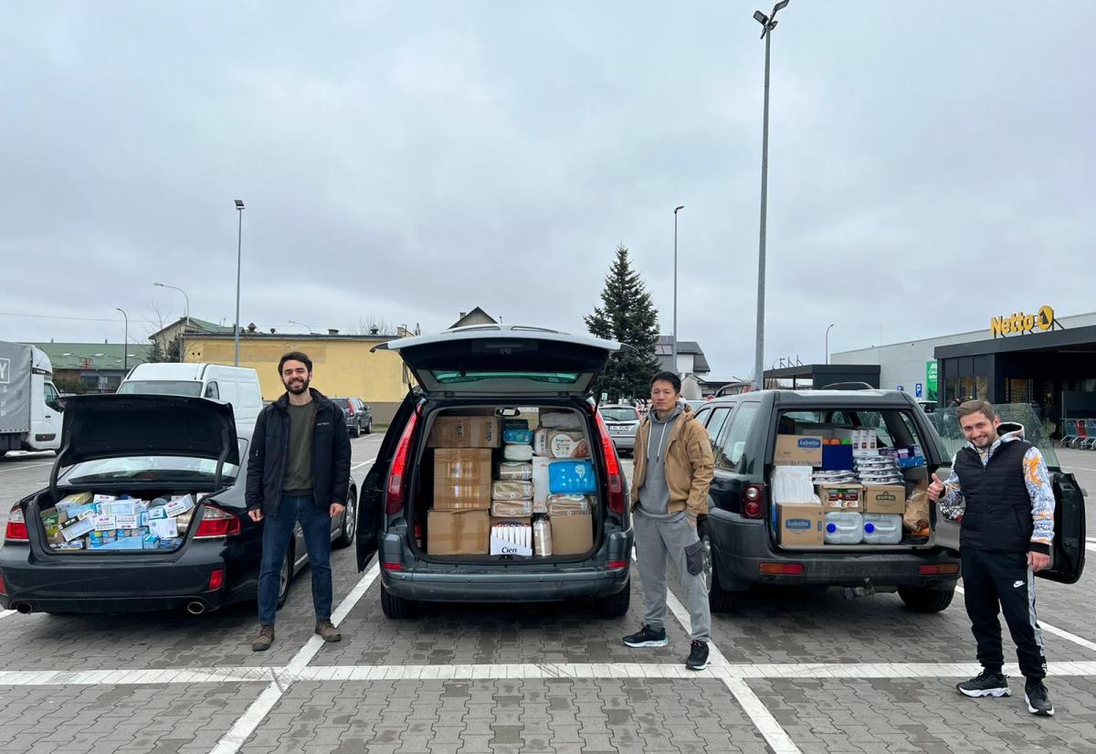 Victor Lal pictured with two colleagues in Poland with cars full of supplies for Ukrainian refugees
