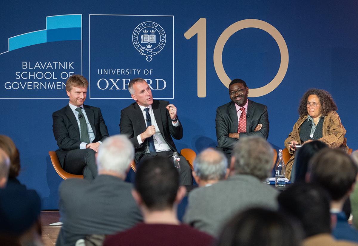 The panellists on stage during the discussion, the background is the Blavatnik School 10 year logo