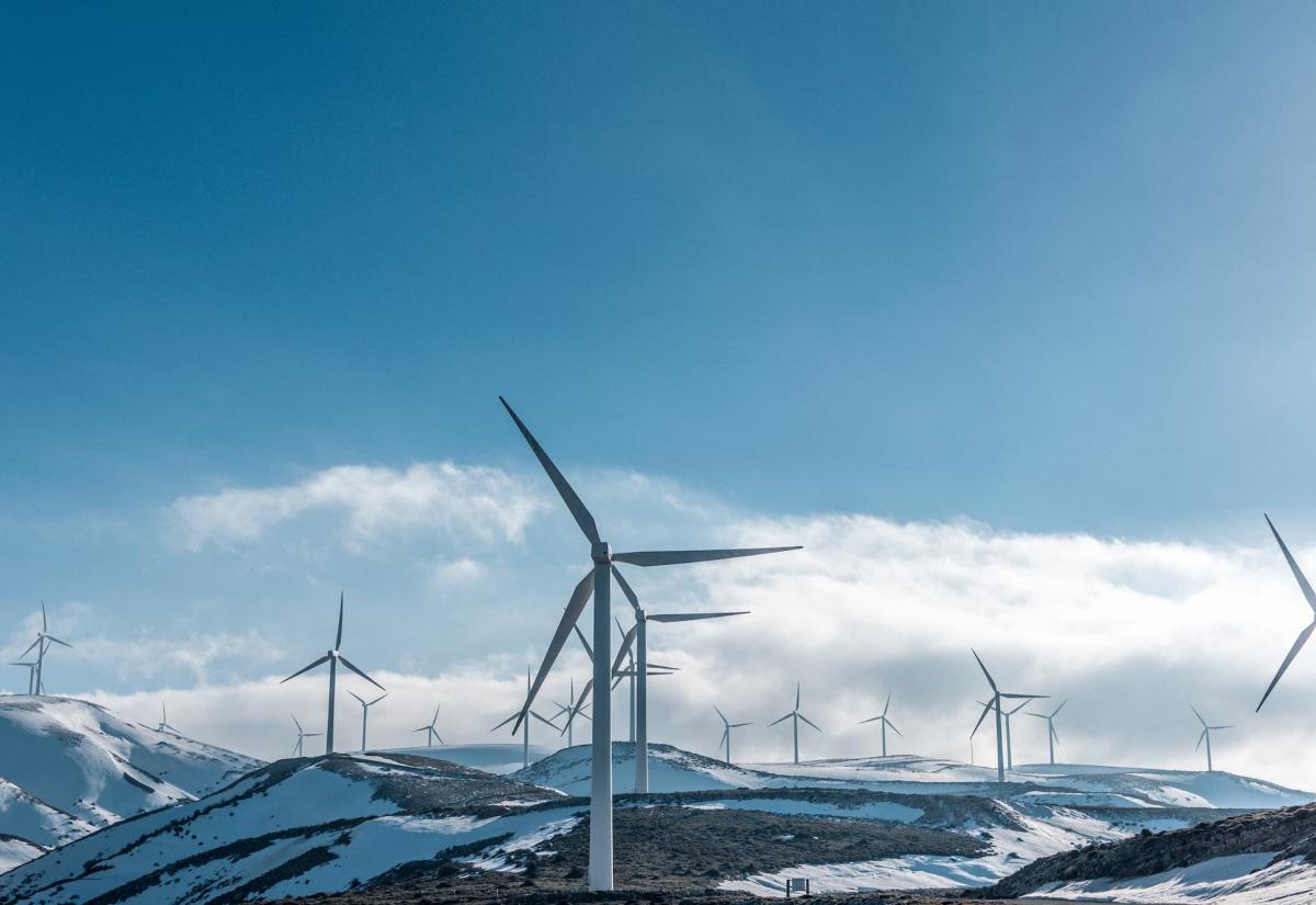Wind turbines across a snowy hilltop – photo by Jason Blackeye from Unsplash