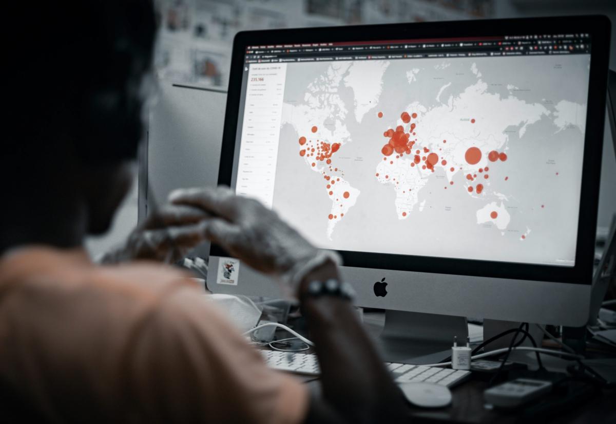 Person looking at computer screen with map of cybersecurity attack virus highlighted