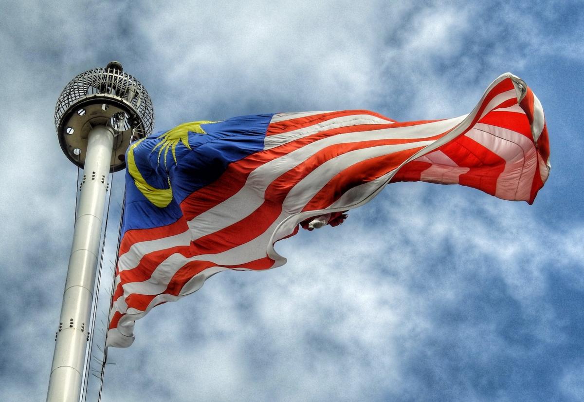 Malaysia flag blows with blue sky and clouds behind