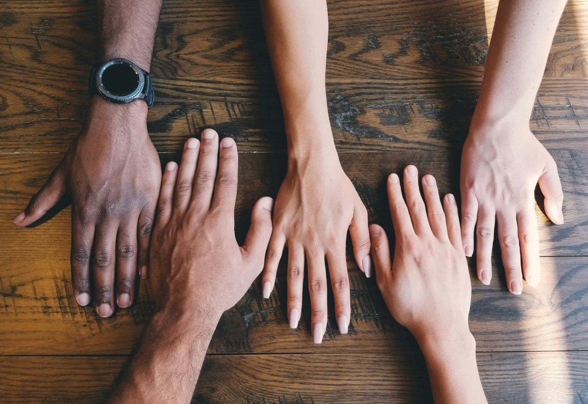 picture of four hands on a table