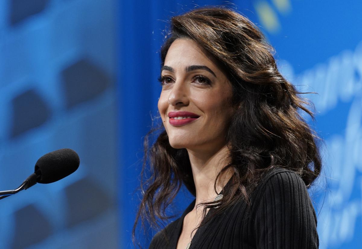 Amal Clooney stands at a conference podium