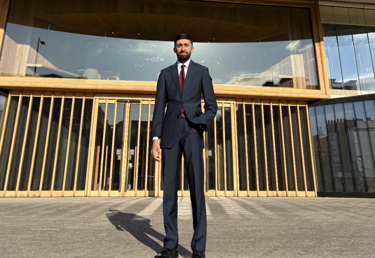 Raees Khan stands in front of the Blavatnik School on a sunny day