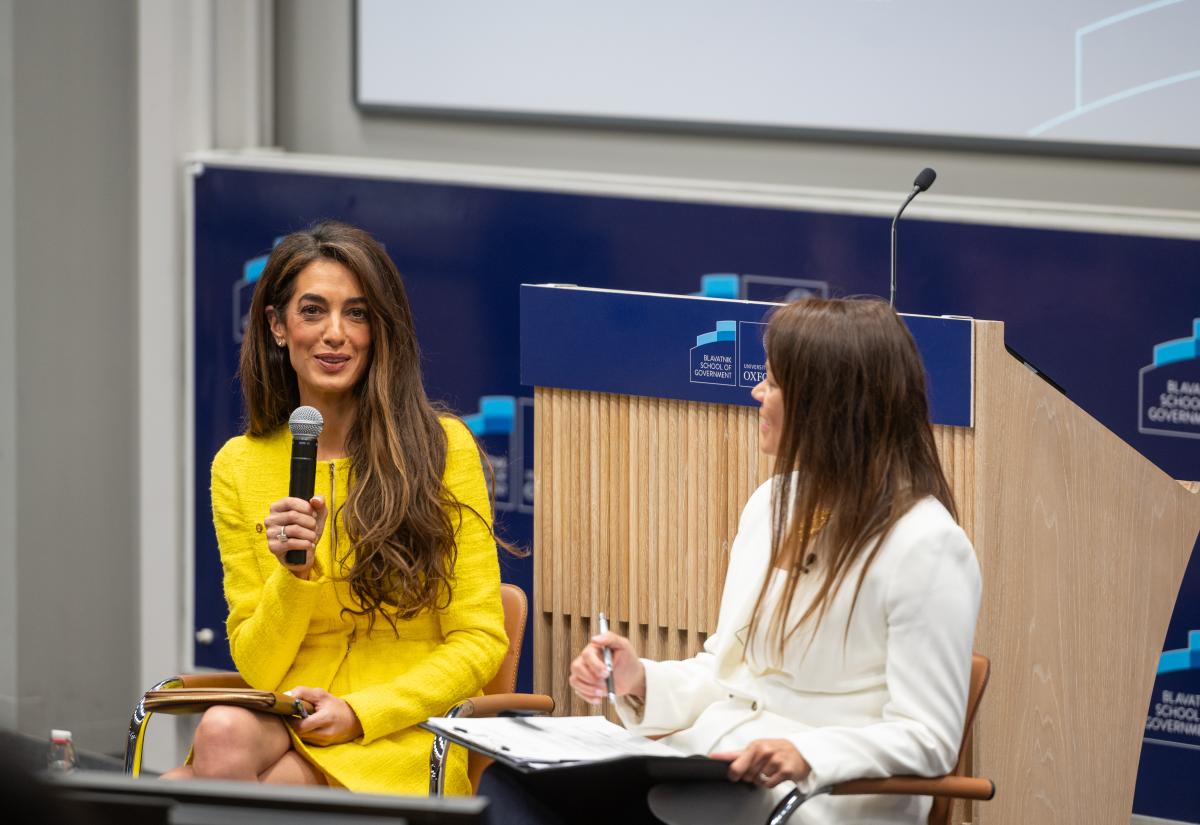 Amal Clooney with a microphone talking to Philippa Webb