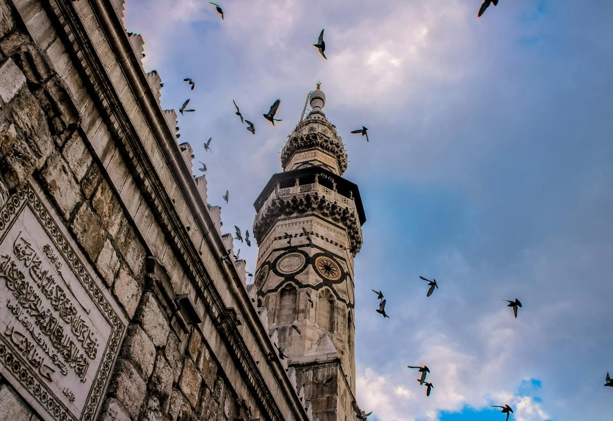 Pigeons fly around a mosque in Damascus