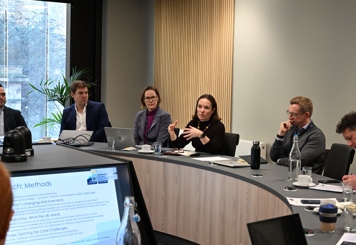 Jenny Bates sits centre with people either side, she is addressing a round table