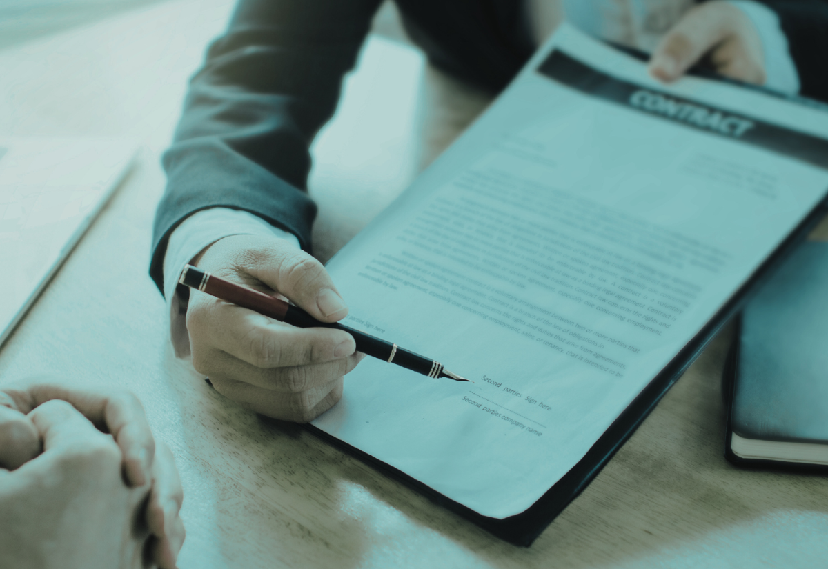 Close-up photo of someone presenting a contract to be signed