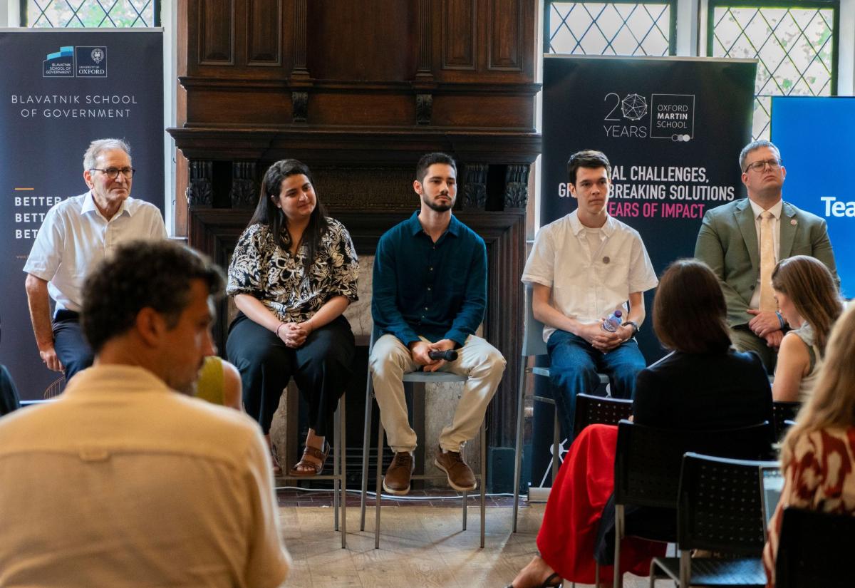 Panel at London Climate week, sat in front of crowd with branded banners behind