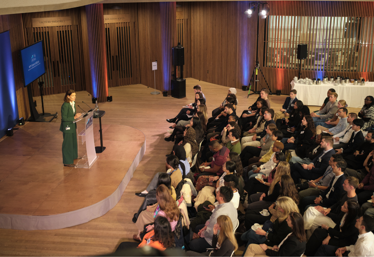 Ngaire Woods gives speech at a lecturn on a small stage as seated students listen