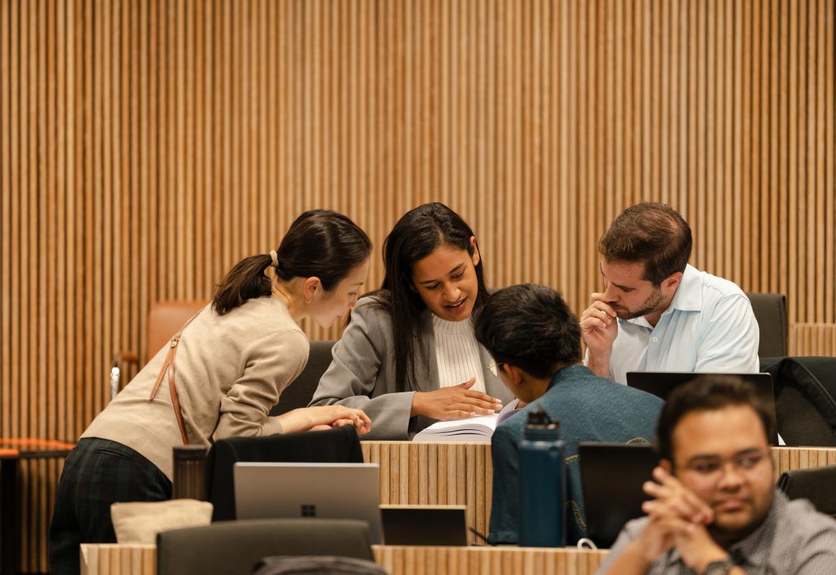 four people huddled together in a lecture room at the Blavatnik School of Government