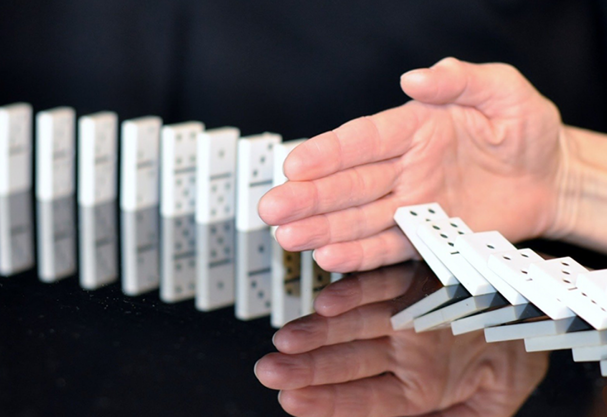 Hand stopping dominoes falling