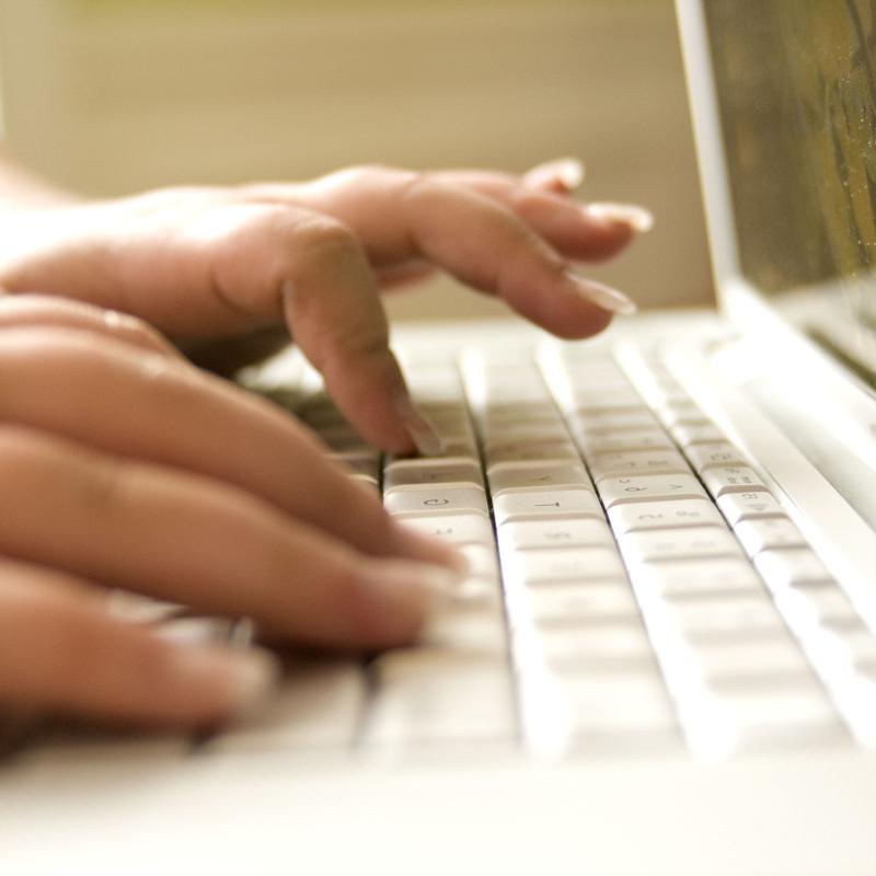 Close-up shot of hands typing on laptop