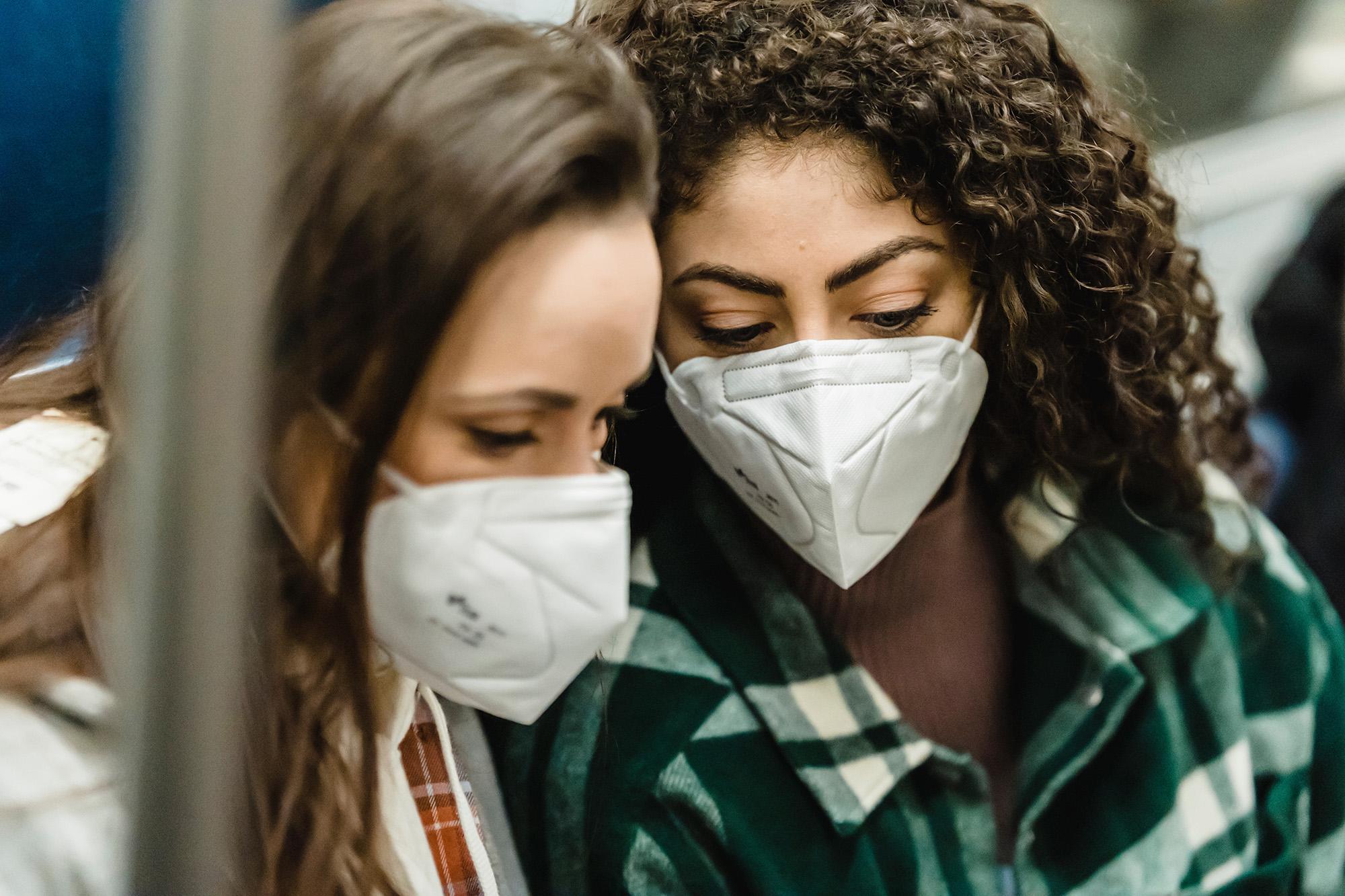 Two young women wearing masks on a train 