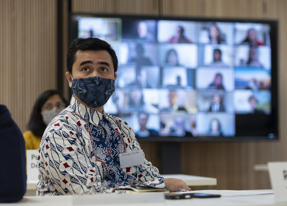 MPP student sitting at a desk during the induction period, with students onscreen in the background as part of hybrid induction